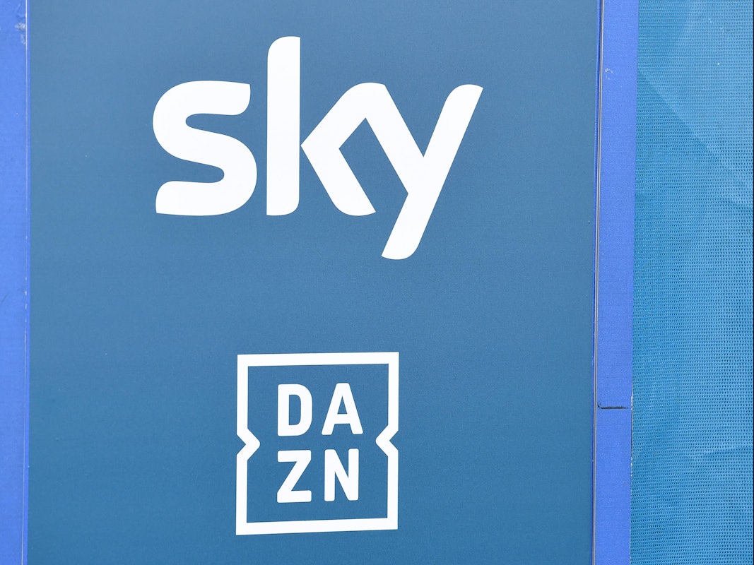 Die Logos der TV-Anbieter Sky und DAZN sind auf eine Tafel gedruckt.