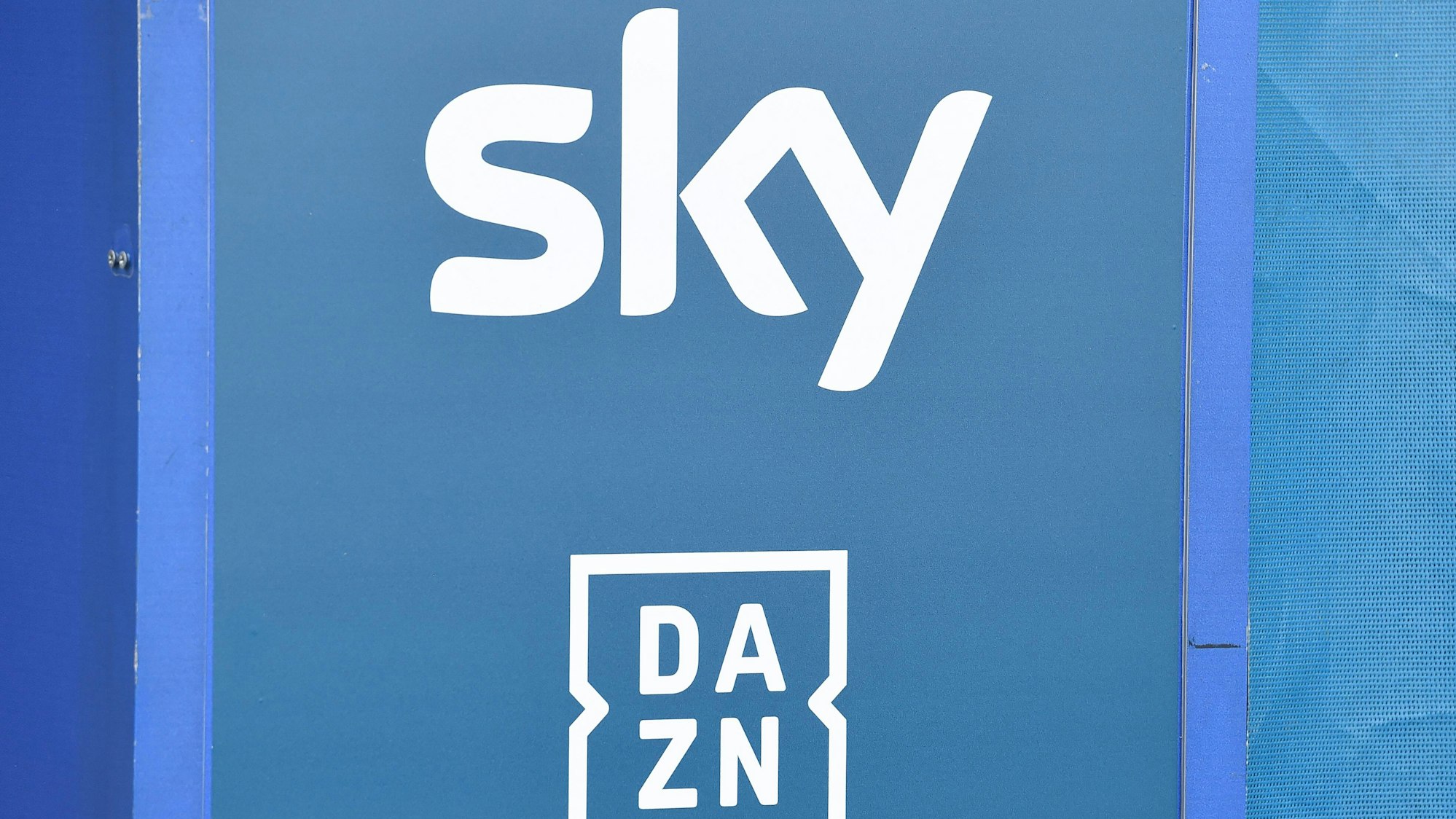 Die Logos der TV-Anbieter Sky und DAZN sind auf eine Tafel gedruckt.