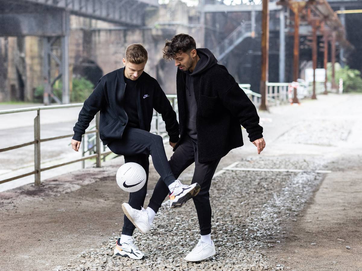 Pascal (l.) und Marcel Gurk halte den Ball vor einer Industrie-Kulisse hoch.