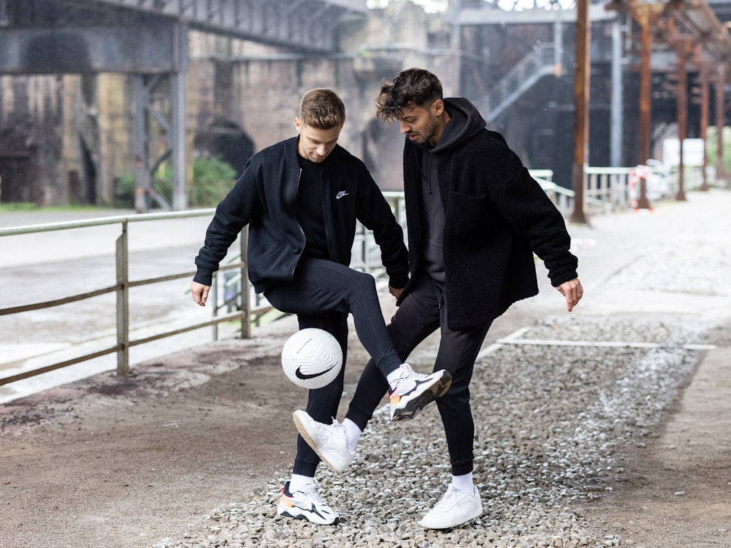 Pascal (l.) und Marcel Gurk halte den Ball vor einer Industrie-Kulisse hoch.