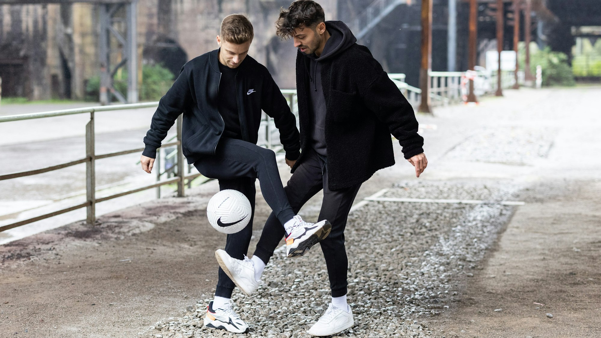 Pascal (l.) und Marcel Gurk halte den Ball vor einer Industrie-Kulisse hoch.