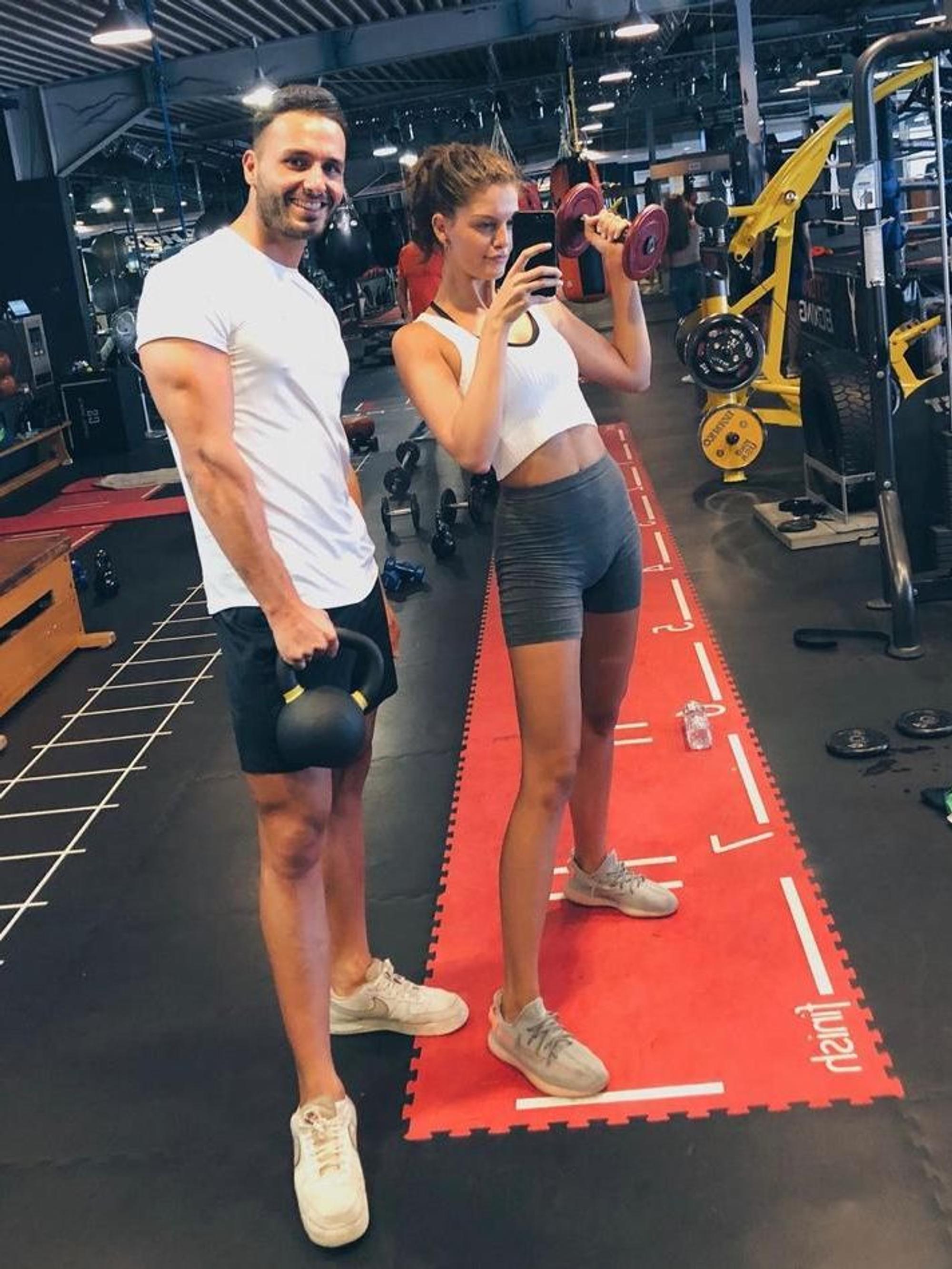 Personal Trainer Oguz Kaan mit Vanessa Fuchs im Fitnessstudio.