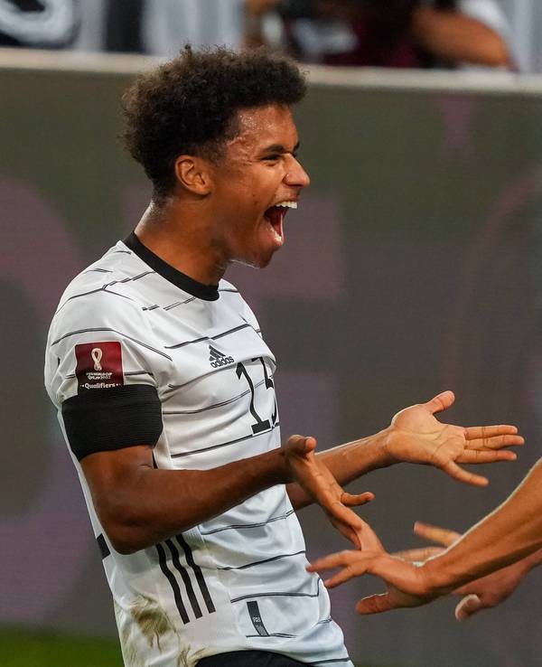 Florian Wirtz geht auf Karim Adeyemi zu. Adeyemi lacht.