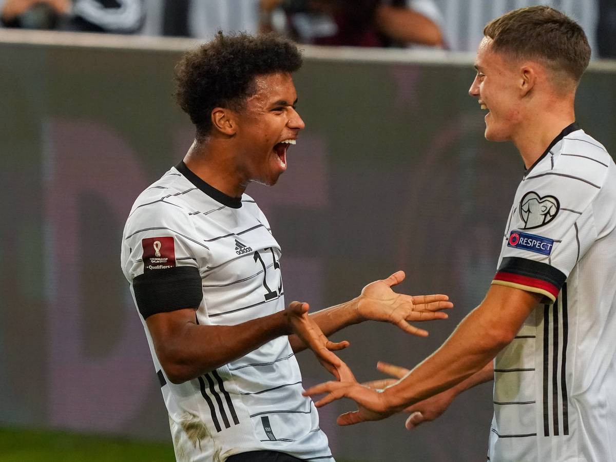 Florian Wirtz geht auf Karim Adeyemi zu. Adeyemi lacht.