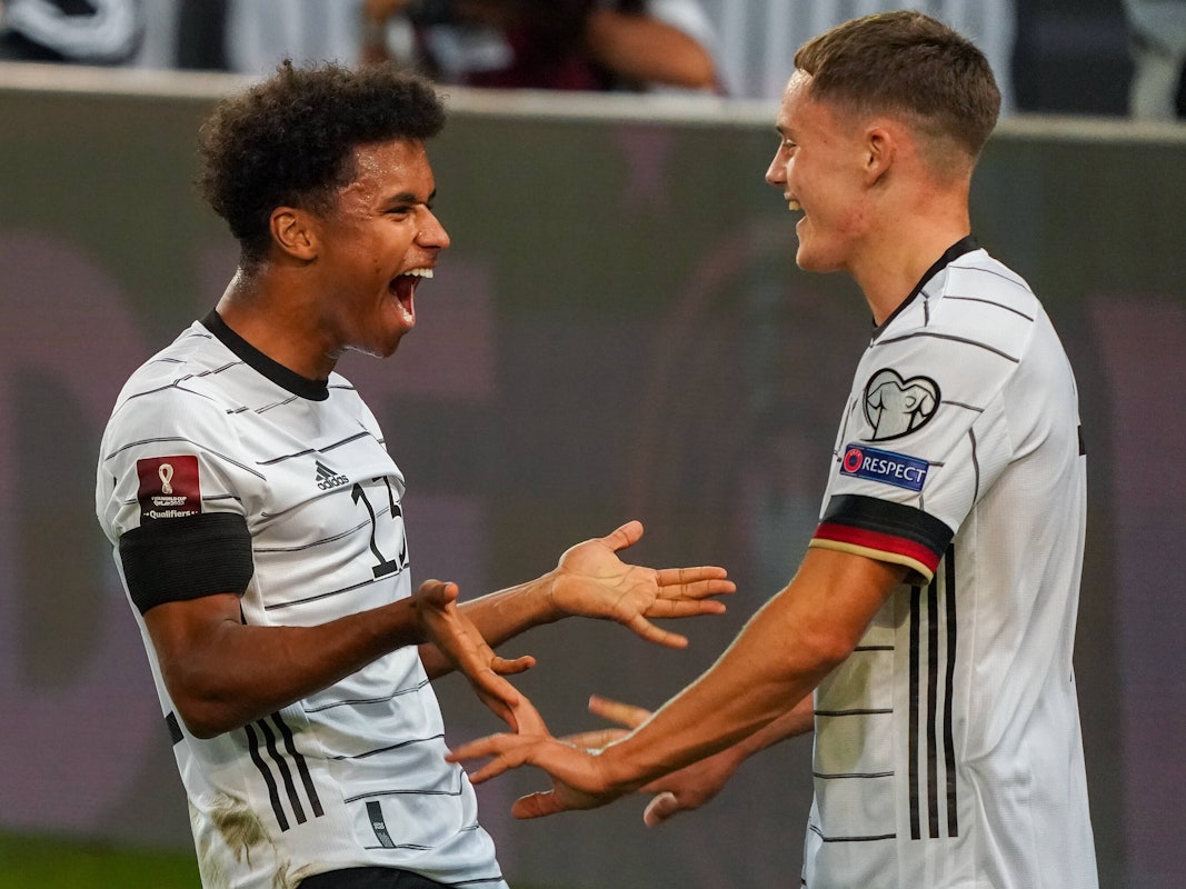 Florian Wirtz geht auf Karim Adeyemi zu. Adeyemi lacht.
