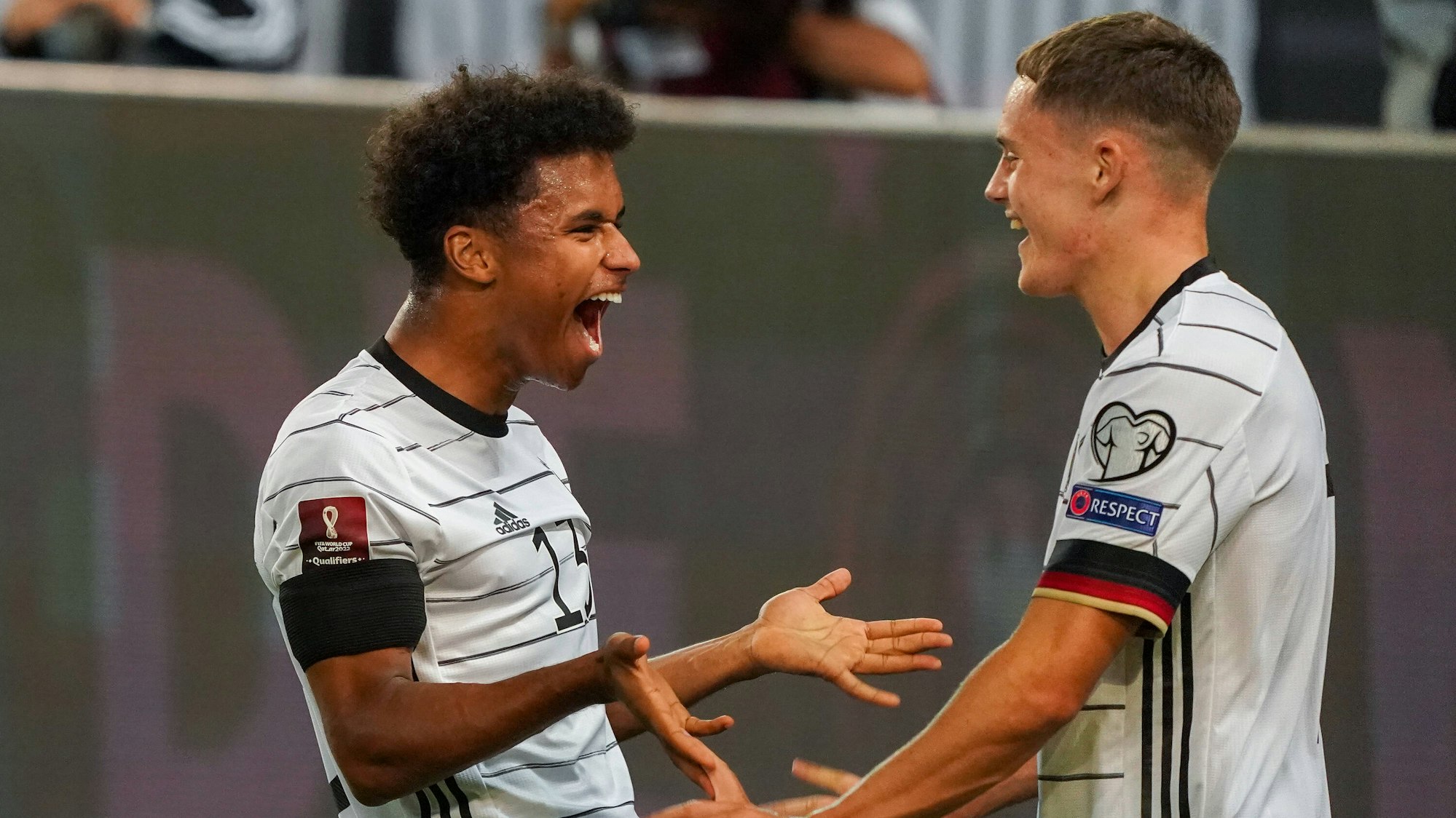 Florian Wirtz geht auf Karim Adeyemi zu. Adeyemi lacht.