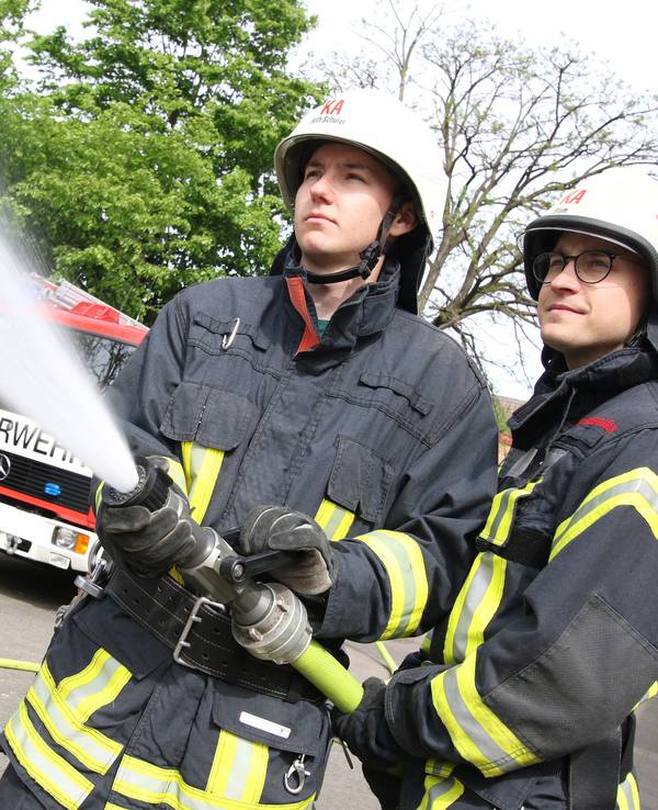 Zwei Feuerwehrmänner halten einen Löschschlauch.