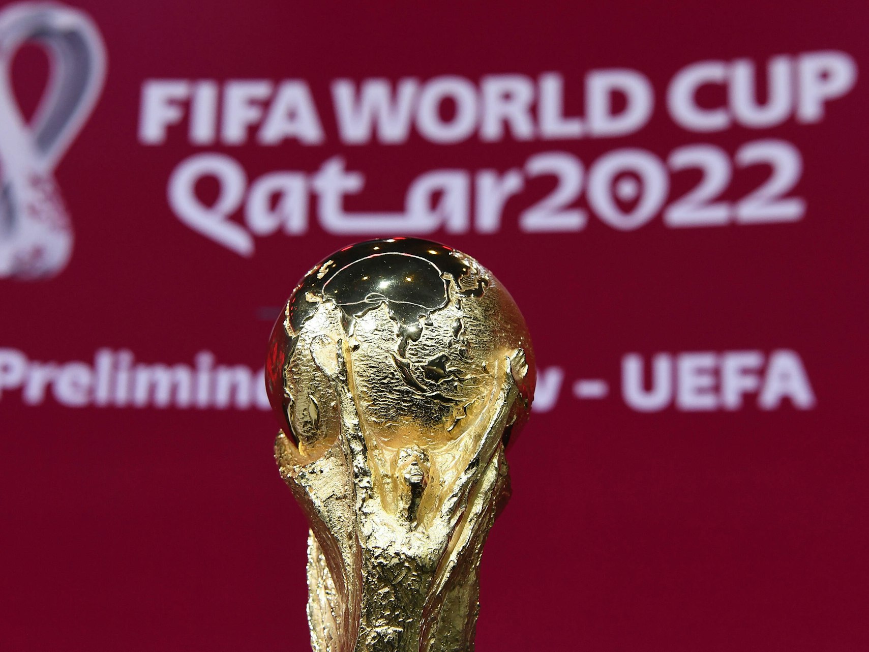 WM-Pokal vor einem Banner der WM 2022 in Katar bei der UEFA-Vorrundenauslosung