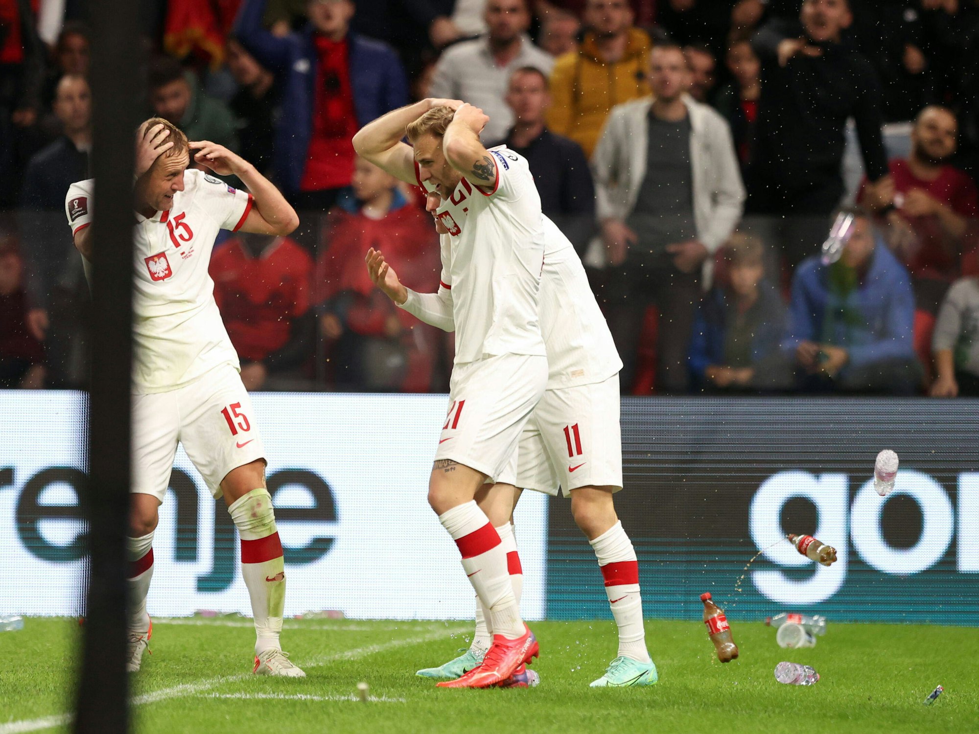 Flaschen fliegen auf die polnischen Spieler, die ihre Köpfe mit den Händen schützen.