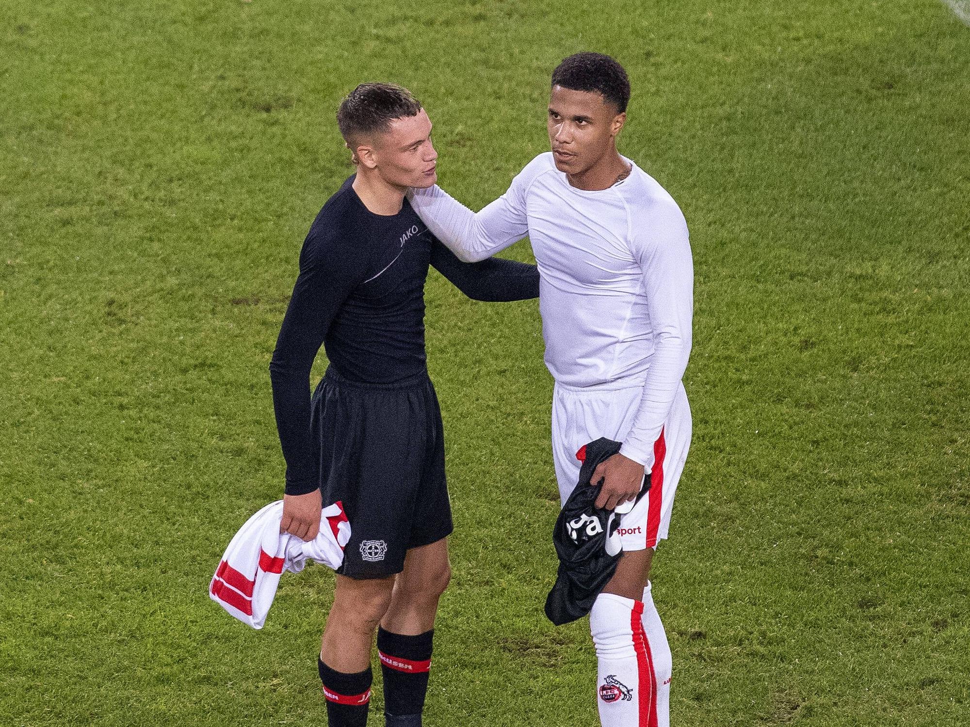 Florian Wirtz und Ismail Jakobs unterhalten sich nach Spielende, beide legen die Arme umeinander.