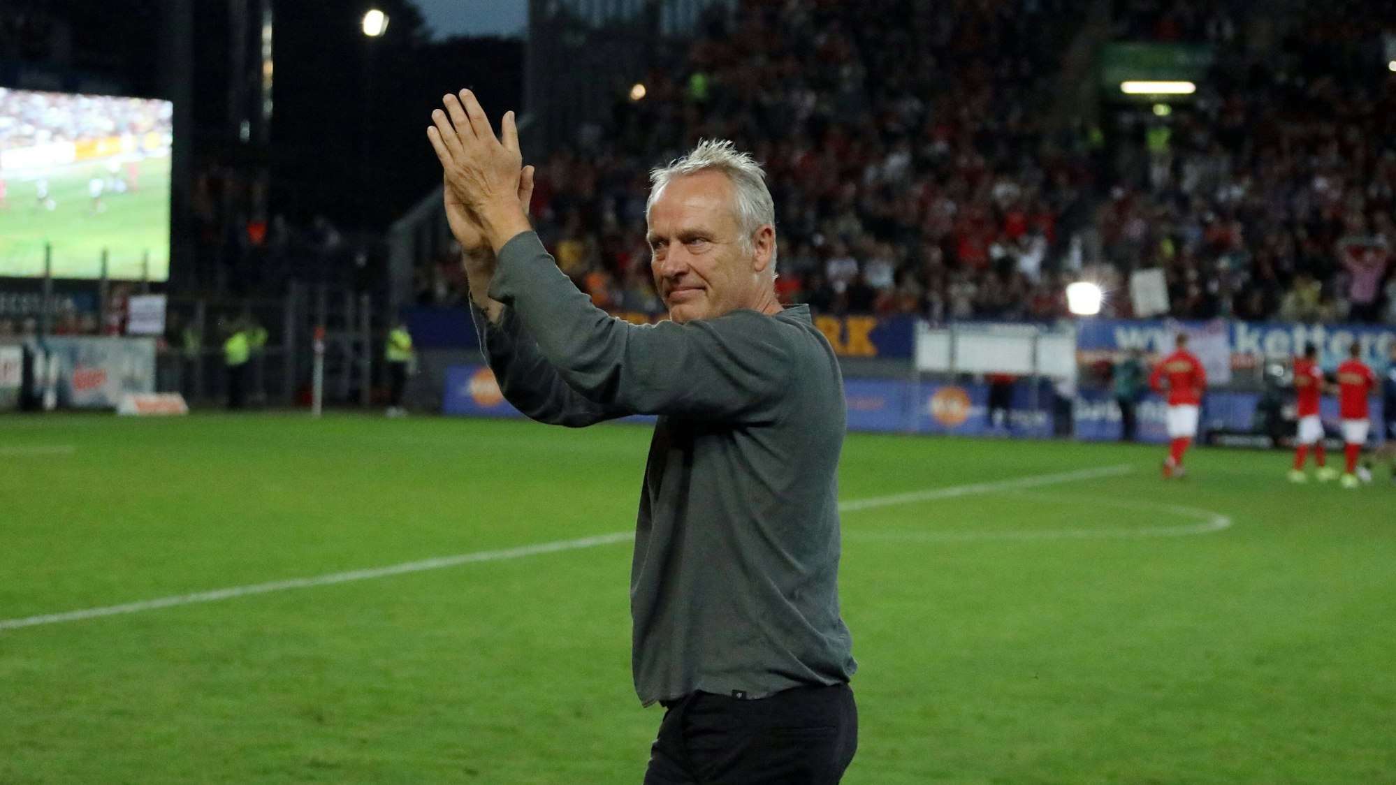 Trainer Christian Streich hat Tränen in den Augen und klatscht in Richtung der Fans auf der Südtribüne.