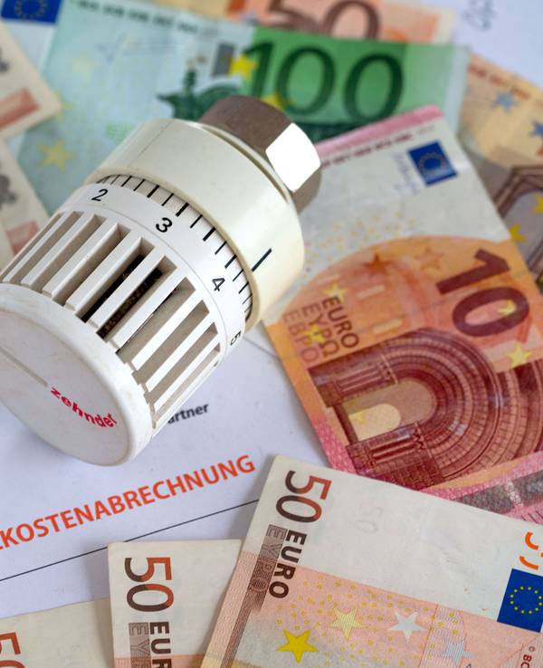 Ein Heizungsthermostat liegt aauf der Heizkostenabrechnung und Euro-Geldscheinen.
