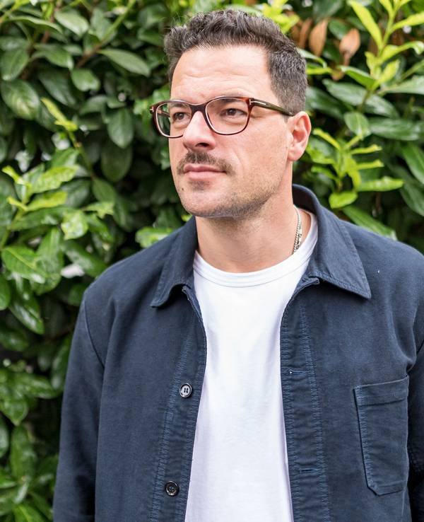 Tobias Licht steht vor einer Hecke in Köln Sülz.