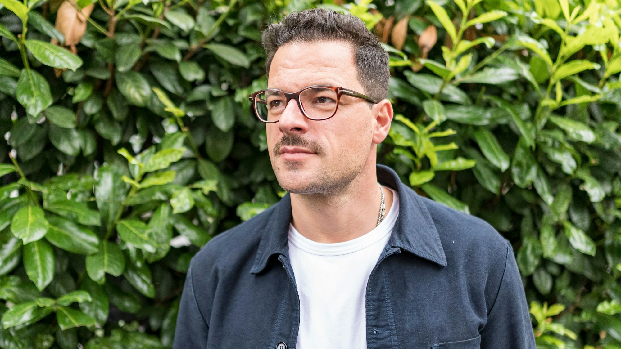 Tobias Licht steht vor einer Hecke in Köln Sülz.