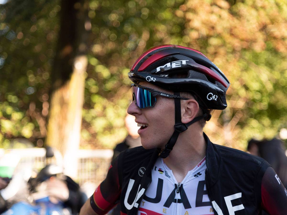 Tadej Pogacar lächelt nach einem langen Rennen. Auf seinem Kopf trägt er einen Helm. Außerdem trägt er eine Sonnenbrille.