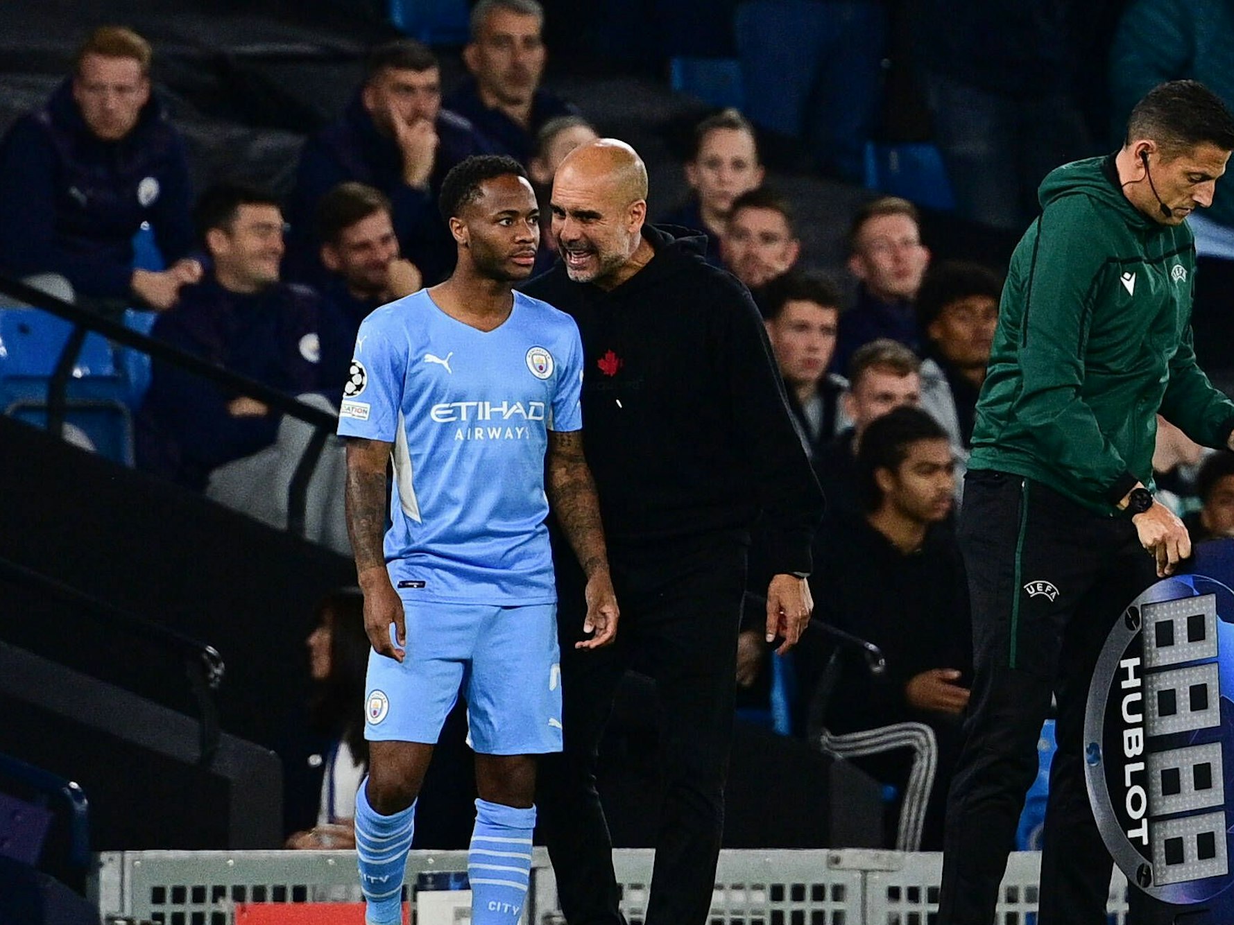 An der Seitenlinie gibt Pep Guardiola Raheem Sterling Anweisungen.