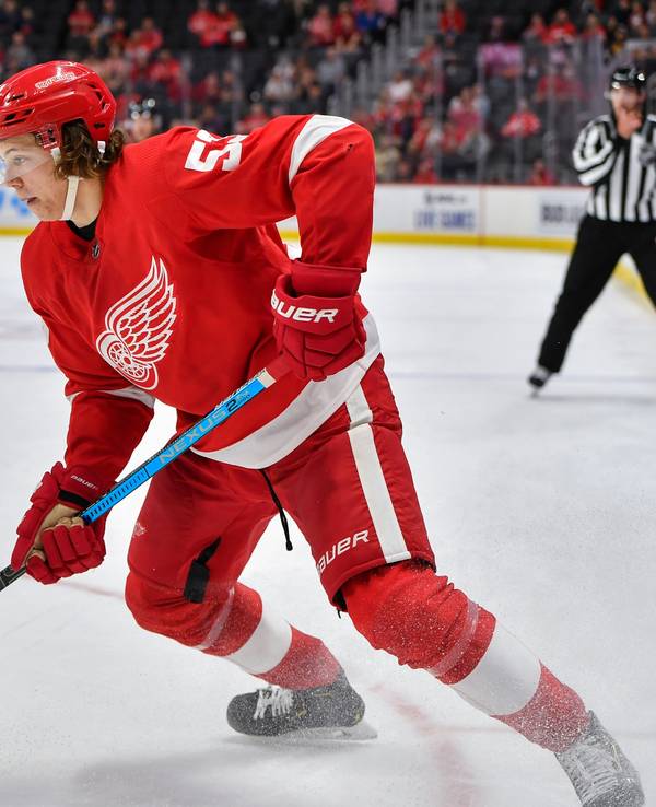 Moritz Seider läuft mit dem roten Trikot der Detroit Red Wings über das Eis und führt den Puck eng am Schläger.