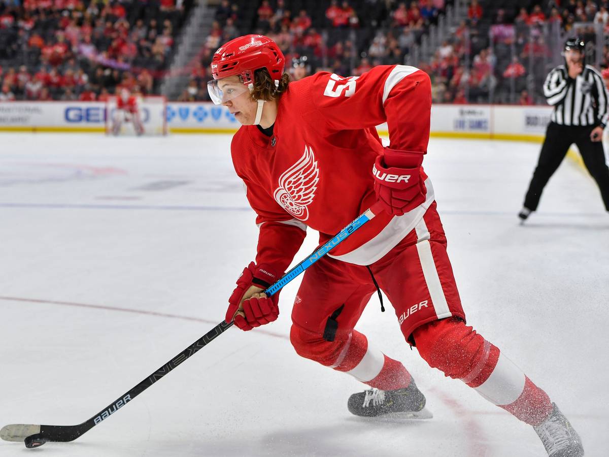 Moritz Seider läuft mit dem roten Trikot der Detroit Red Wings über das Eis und führt den Puck eng am Schläger.