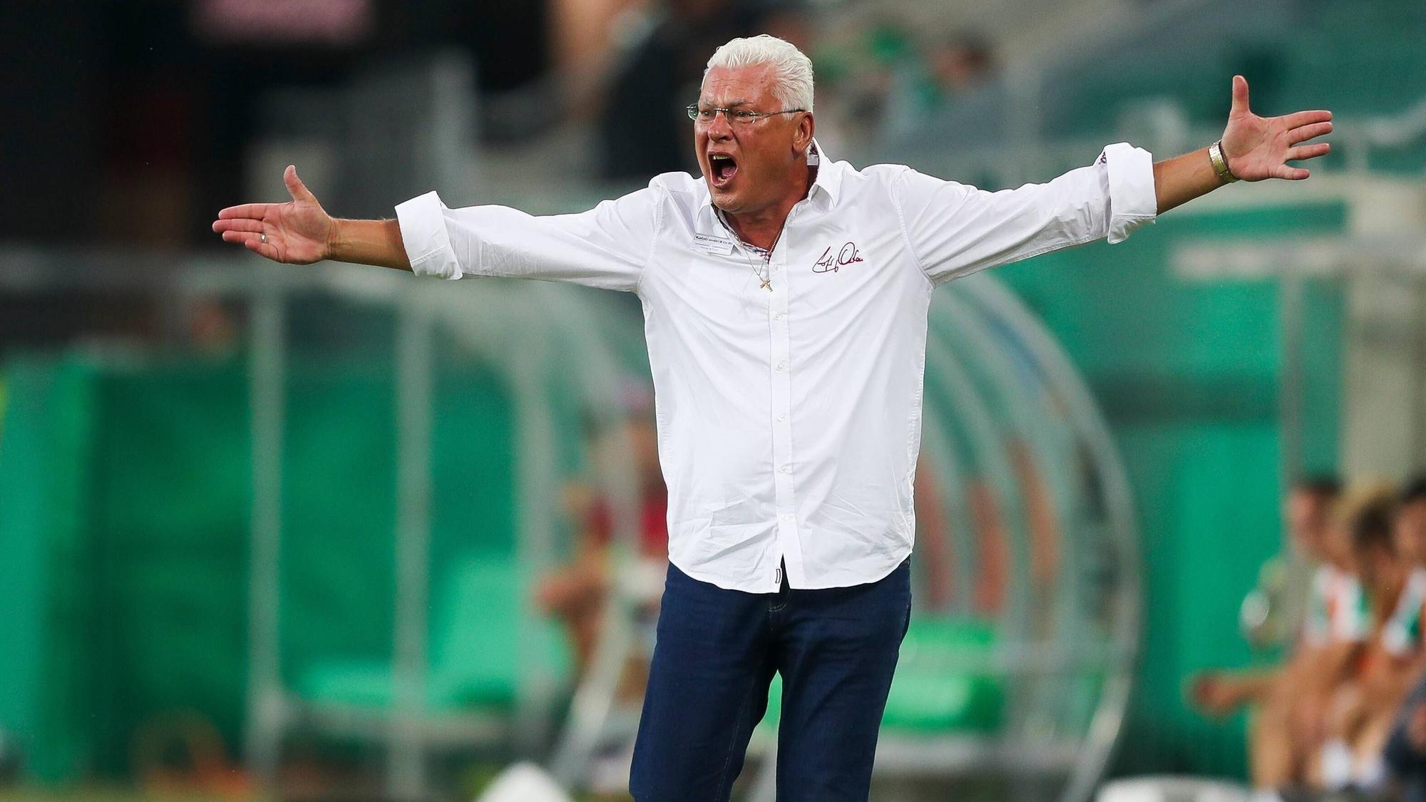 Toni Polster steht an der Seitenlinie und breitet die Arme aus