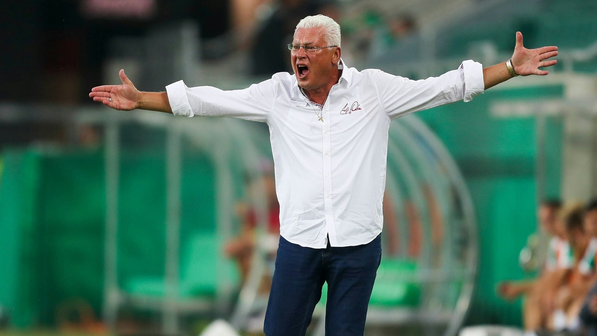 Toni Polster steht an der Seitenlinie und breitet die Arme aus