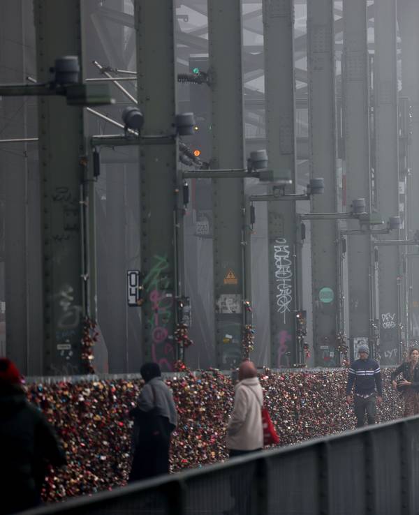 Spaziergänger gehen im Nebel über die Hohenzollernbrücke.