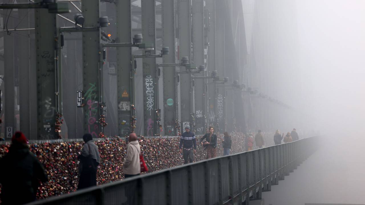 Spaziergänger gehen im Nebel über die Hohenzollernbrücke.