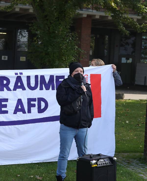 Eine Aktivistin steht vor einem Plakat.