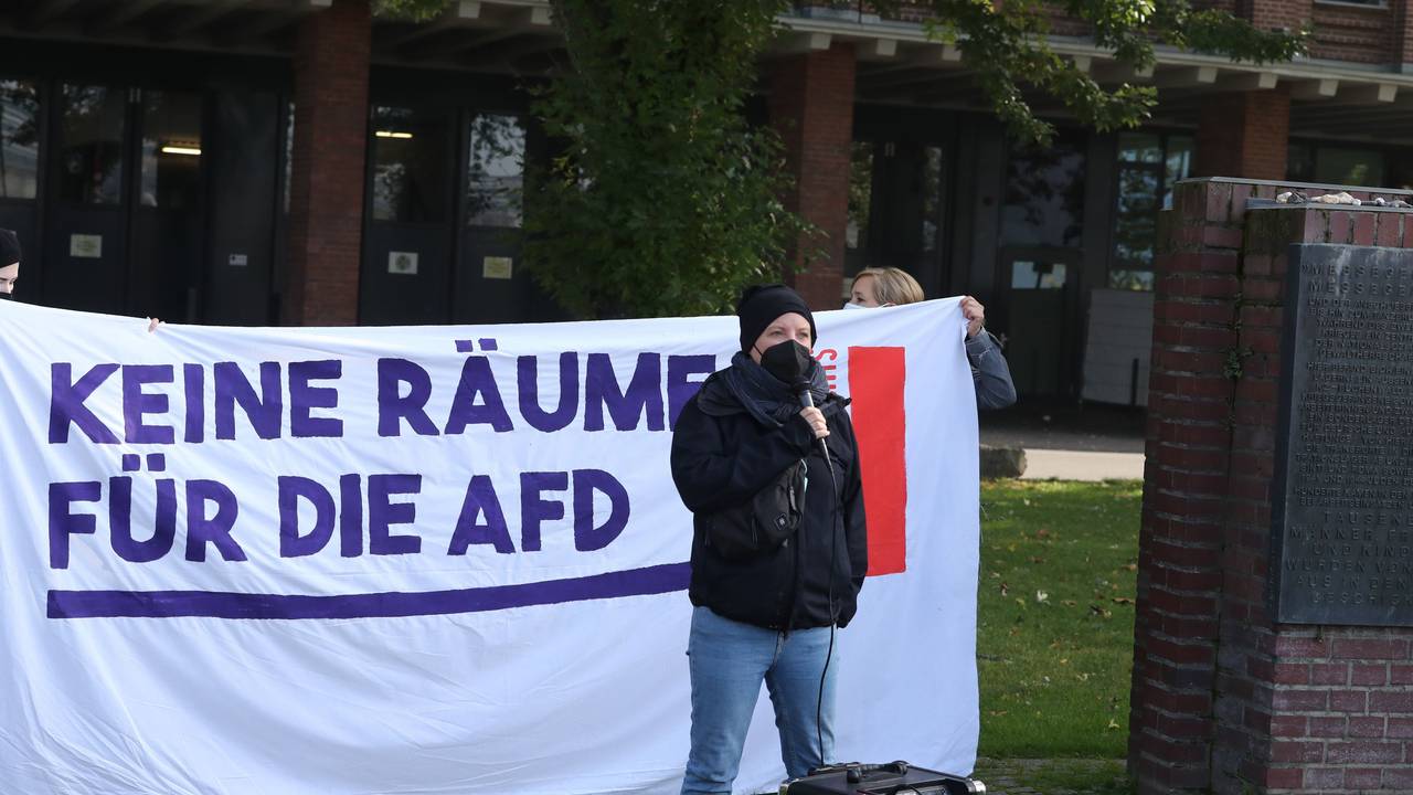 Eine Aktivistin steht vor einem Plakat.