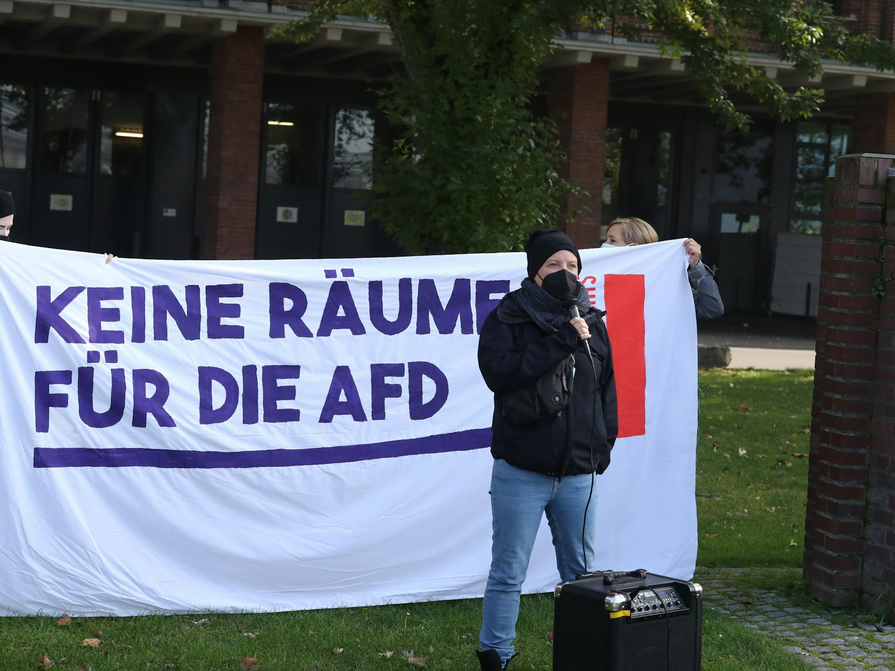 Eine Aktivistin steht vor einem Plakat.