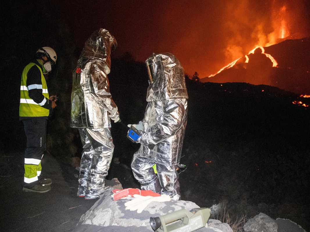 In der Flammenhölle untersuchen Mitarbeiter der Militärischen Nothilfeeinheit in Spezialanzügen die Lava.
