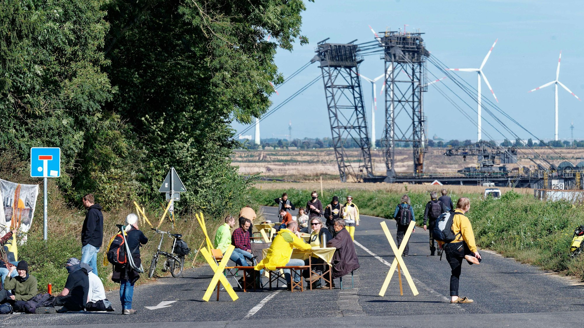 Bei der Aktion „Platz nehmen für Lützerath“ sitzen Teilnehmer mit Stühlen und Tischen im Ort Lützerath auf der Straße am Tagebaurand.