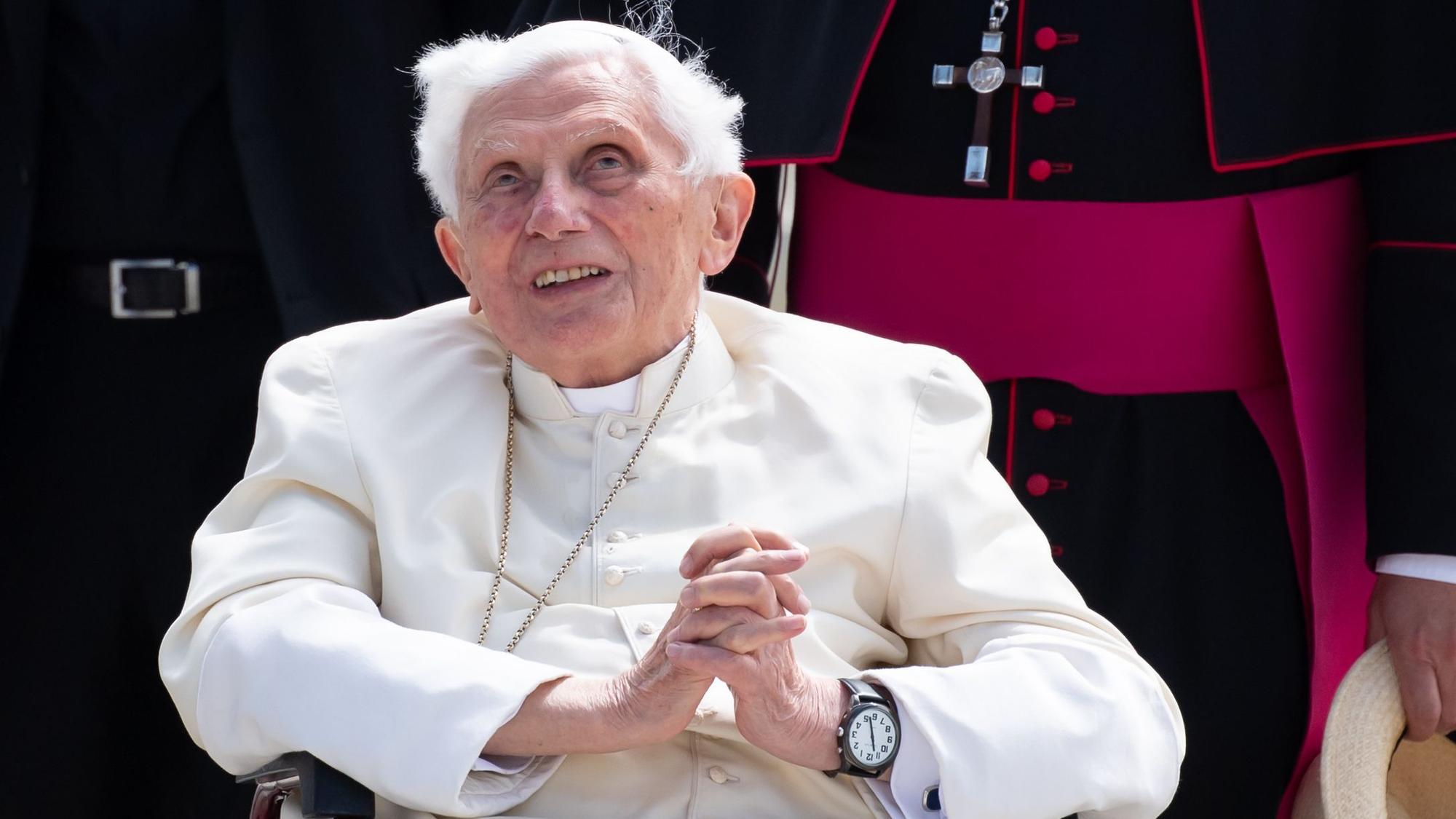 Der emeritierte Papst Benedikt XVI. bei einem Besuch in München 2020, er sitzt in einem Rollstuhl und hat die Hände gefaltet.
