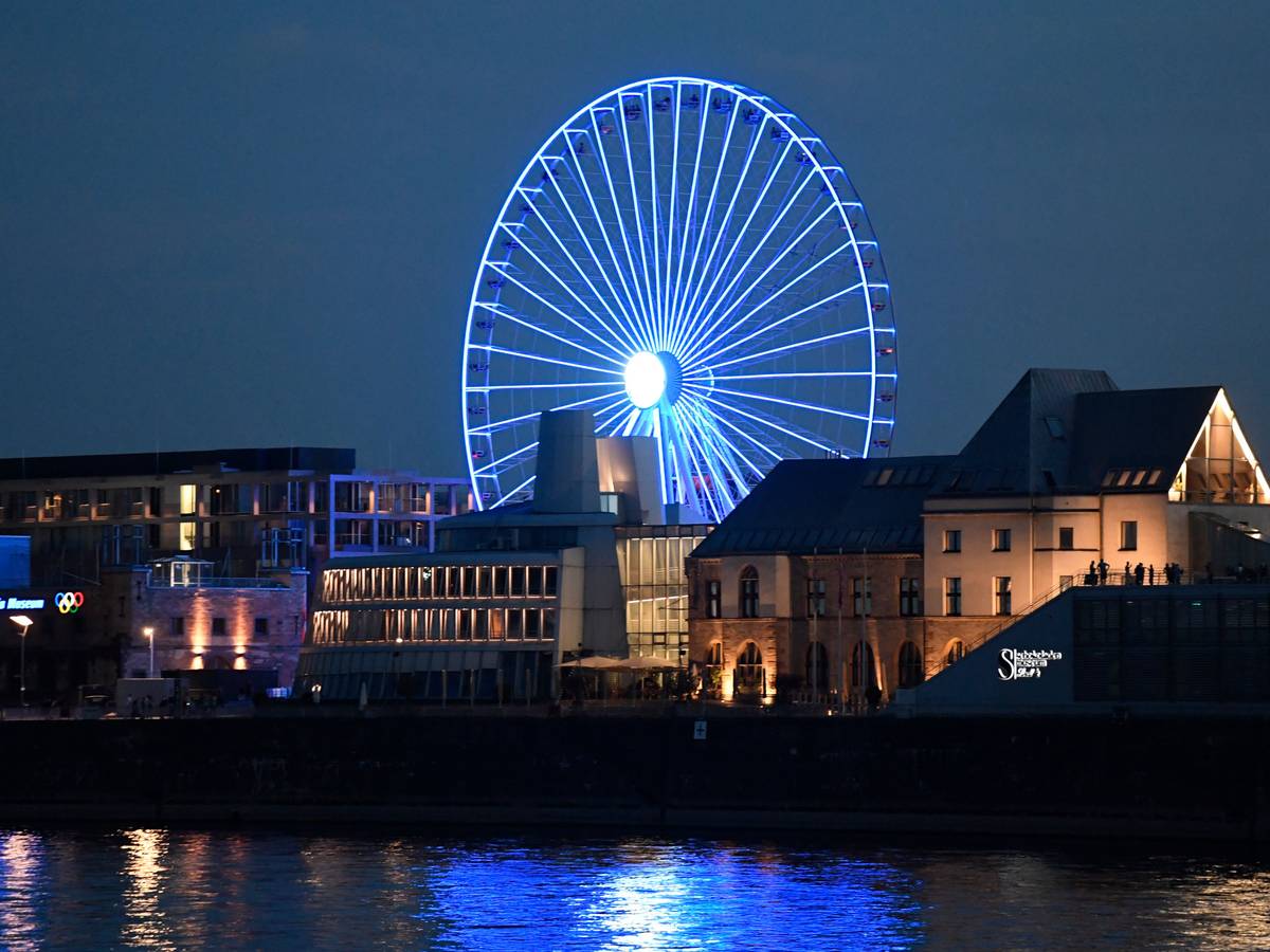 Das Riesenrad am Rheinufer strahlt bei Nacht.