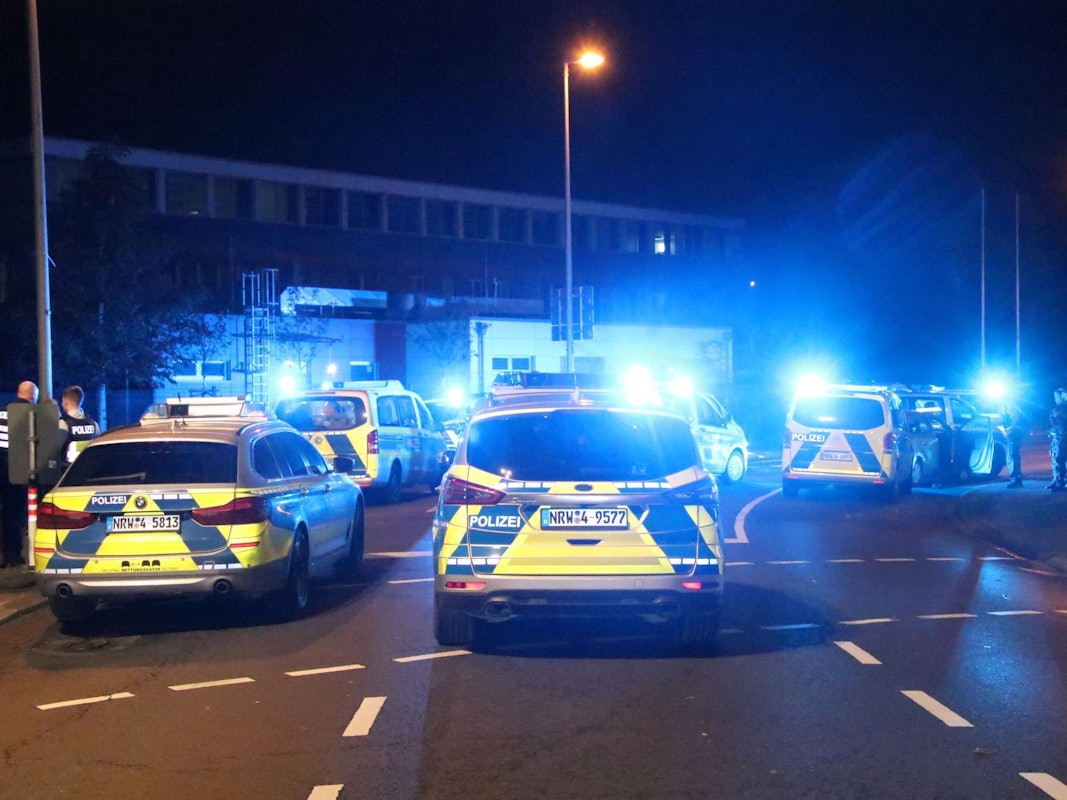 Streifenwagen stehen nachts auf einer Straße.