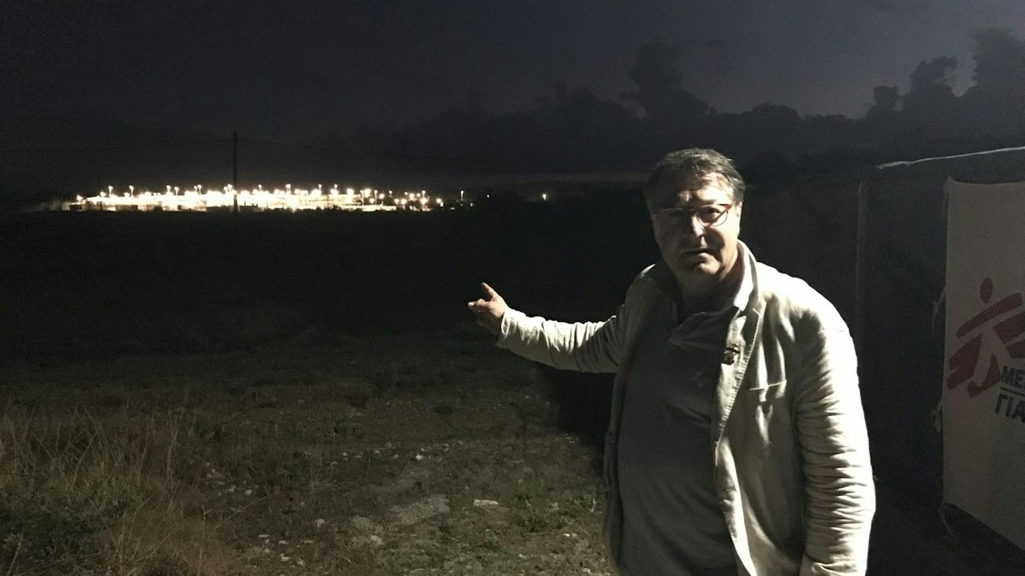 Hans Mörtter von der Lutherkirche Südstadt zeigt auf das nachts erleuchtete Flüchtlingslager.