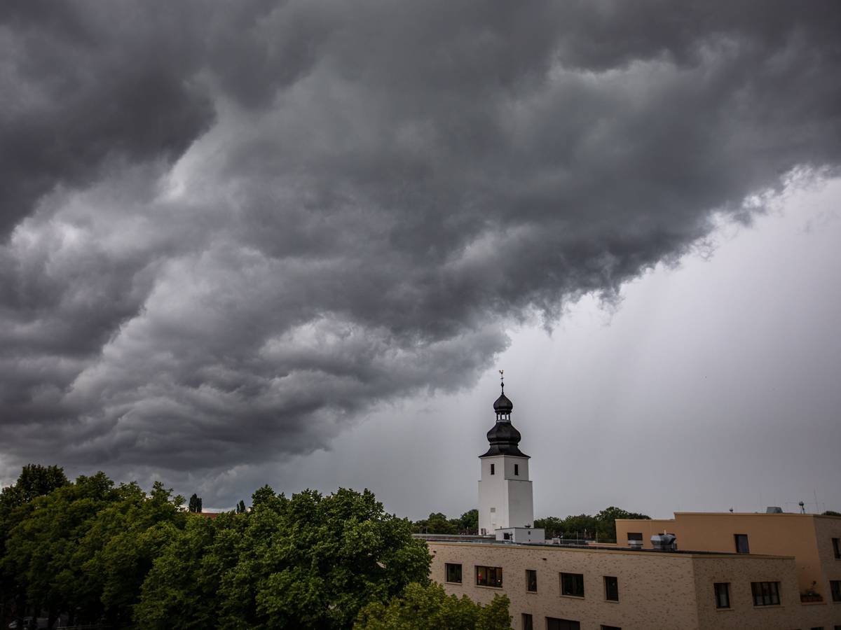 Dunkle Wolken ziehen am 4. Juli 2021 kurz vor einem Gewitter mit Starkregen über den Kölner Ortsteil Sülz. Der Kirchturm rechts gehört zur Kirche „Zur heiligen Familie“.