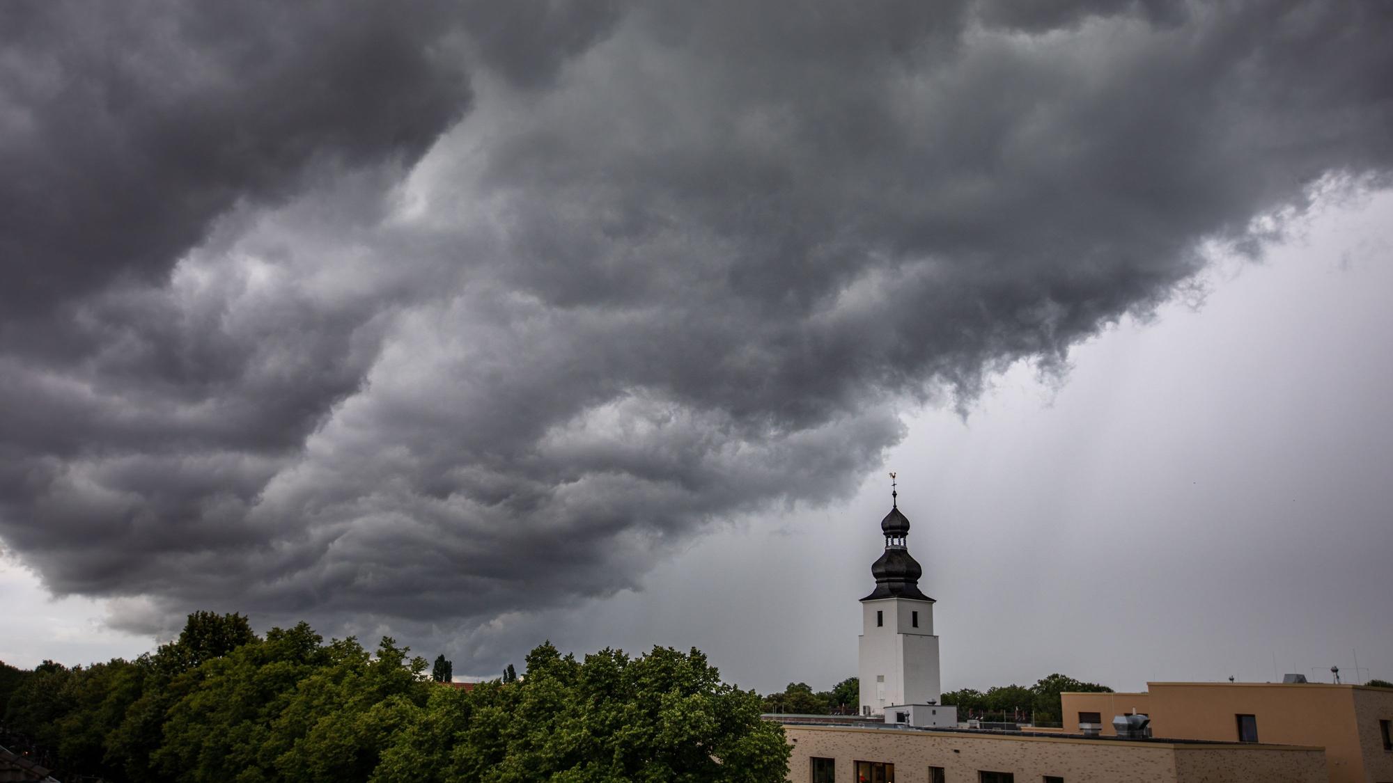 Dunkle Wolken ziehen am 4. Juli 2021 kurz vor einem Gewitter mit Starkregen über den Kölner Ortsteil Sülz. Der Kirchturm rechts gehört zur Kirche „Zur heiligen Familie“.