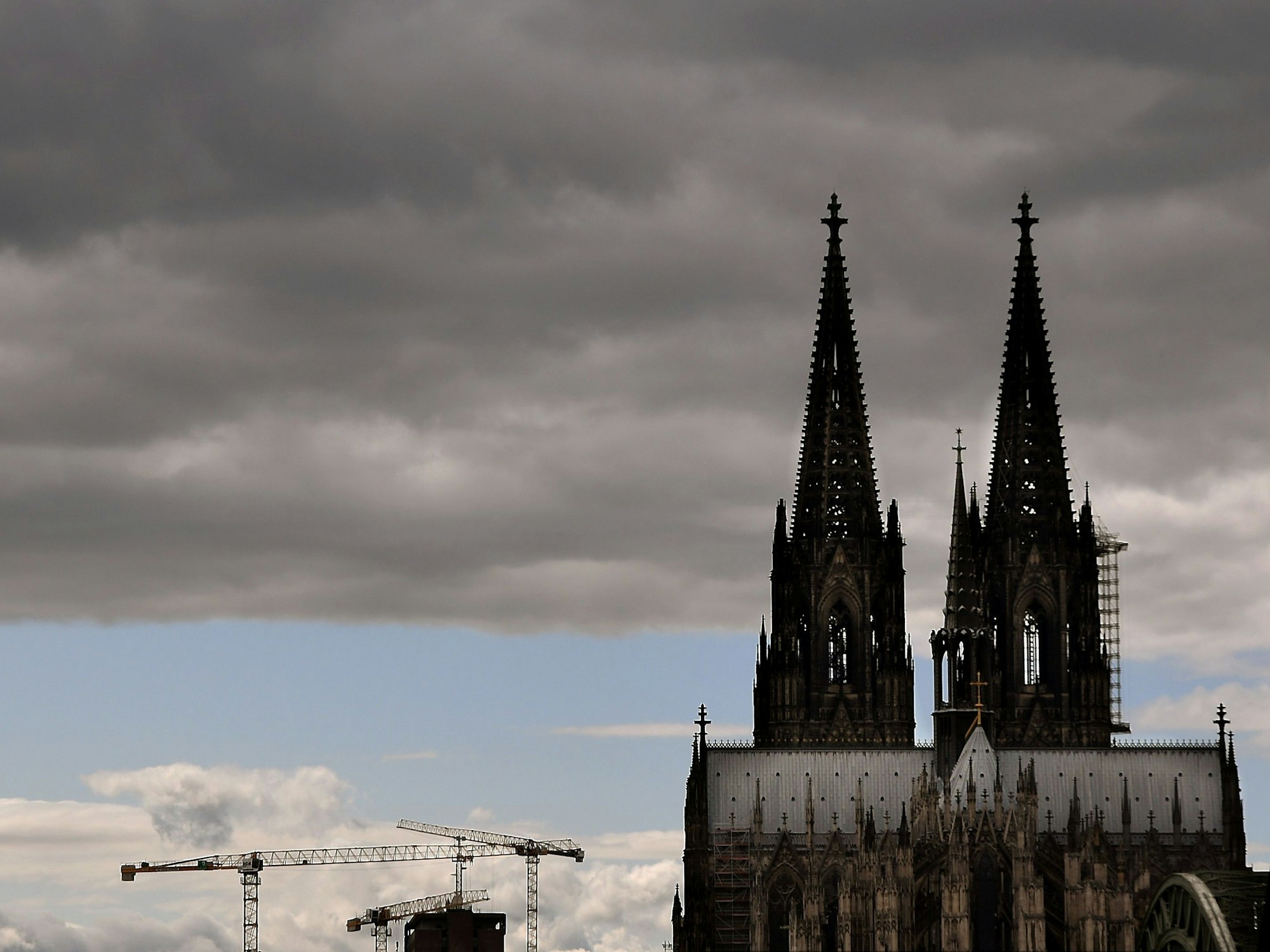 Der Kölner Dom mit seinen Turmspitzen kratzt an den dunklen Wolken.