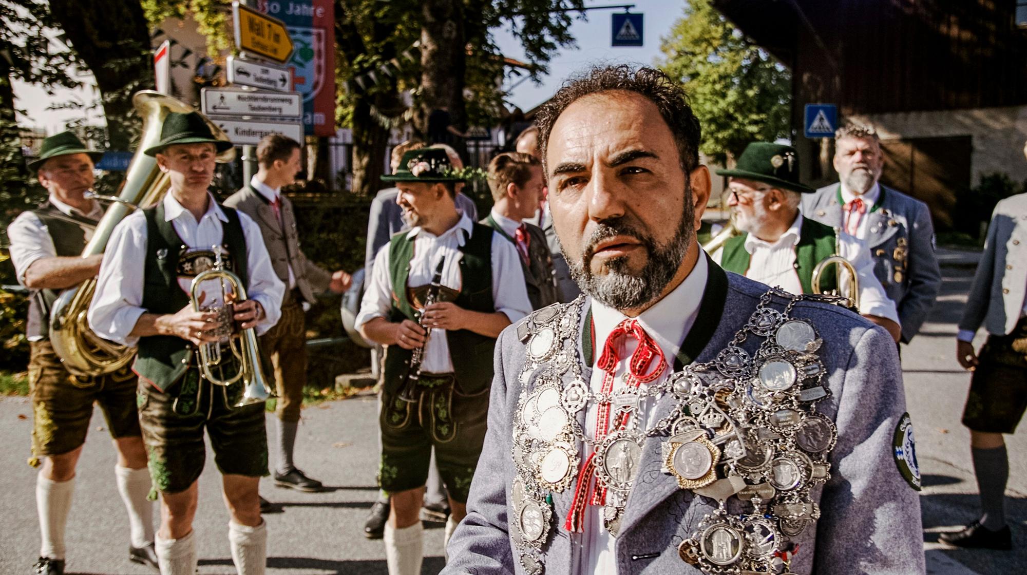 Adnan Maral steht in Tracht vor einer Blaskapelle.