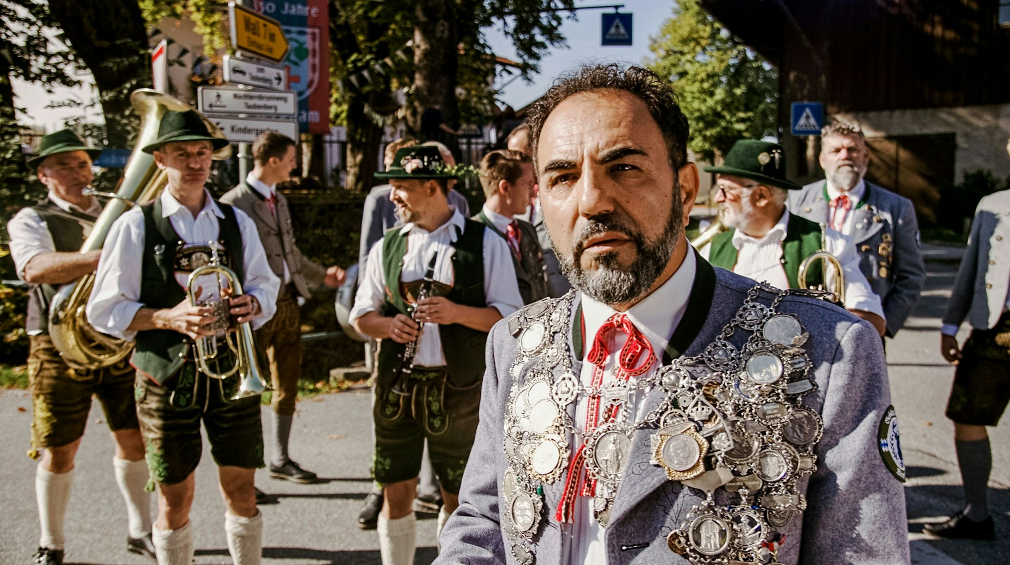 Adnan Maral steht in Tracht vor einer Blaskapelle.