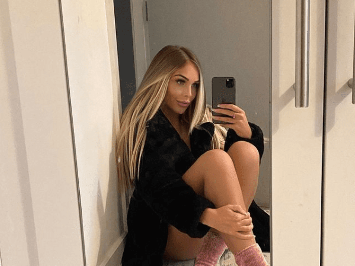 Ava Grace posiert auf einem Instagram-Foto vom 19. Oktober 2021 mit rosa-farbigen Socken und einem schwarzen Mantel vor einem Spiegel.