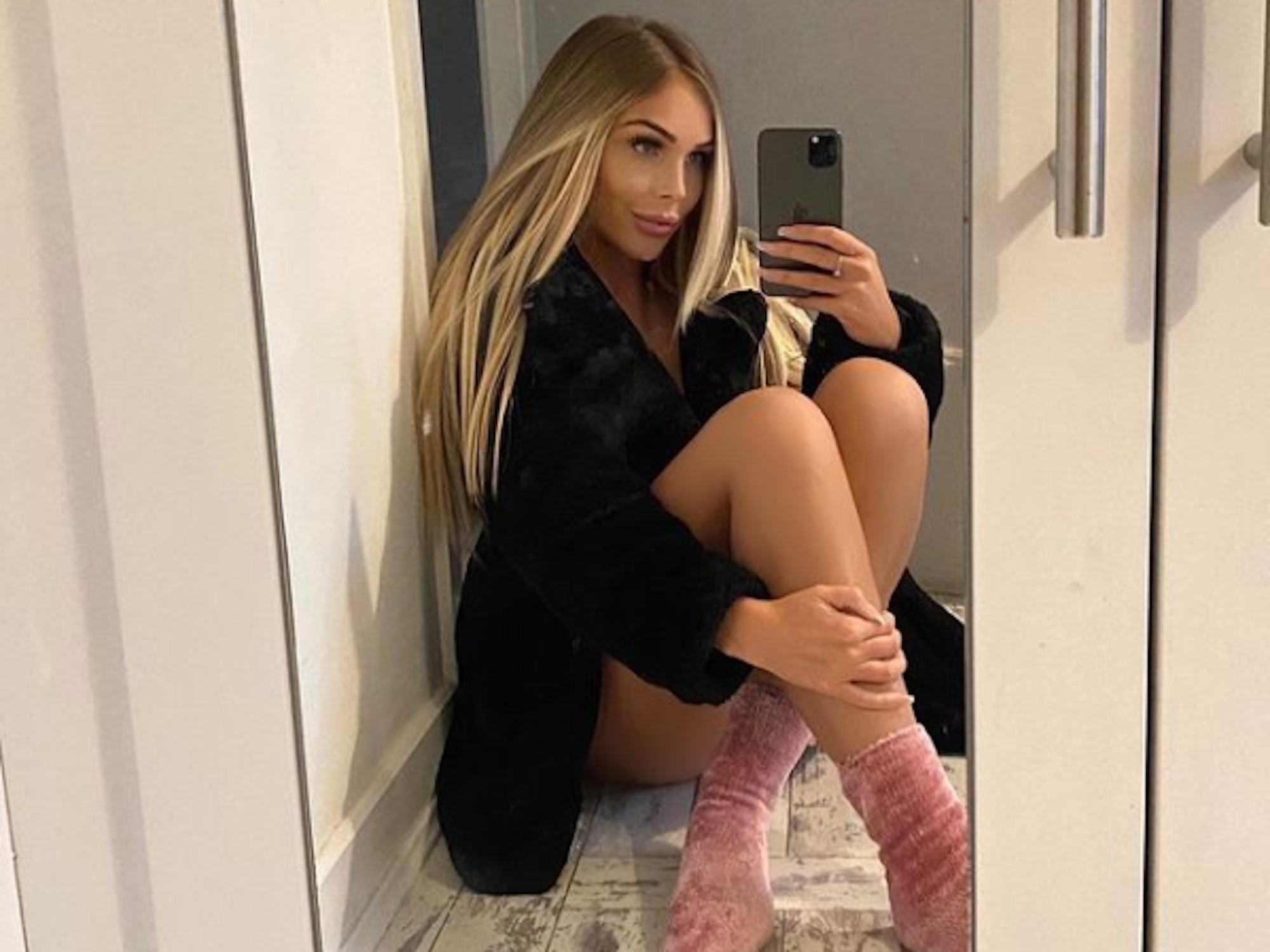 Ava Grace posiert auf einem Instagram-Foto vom 19. Oktober 2021 mit rosa-farbigen Socken und einem schwarzen Mantel vor einem Spiegel.