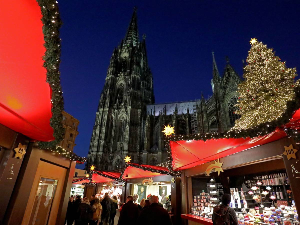 Besucher gehen über den Weihnachtsmarkt vor dem Kölner Dom.
