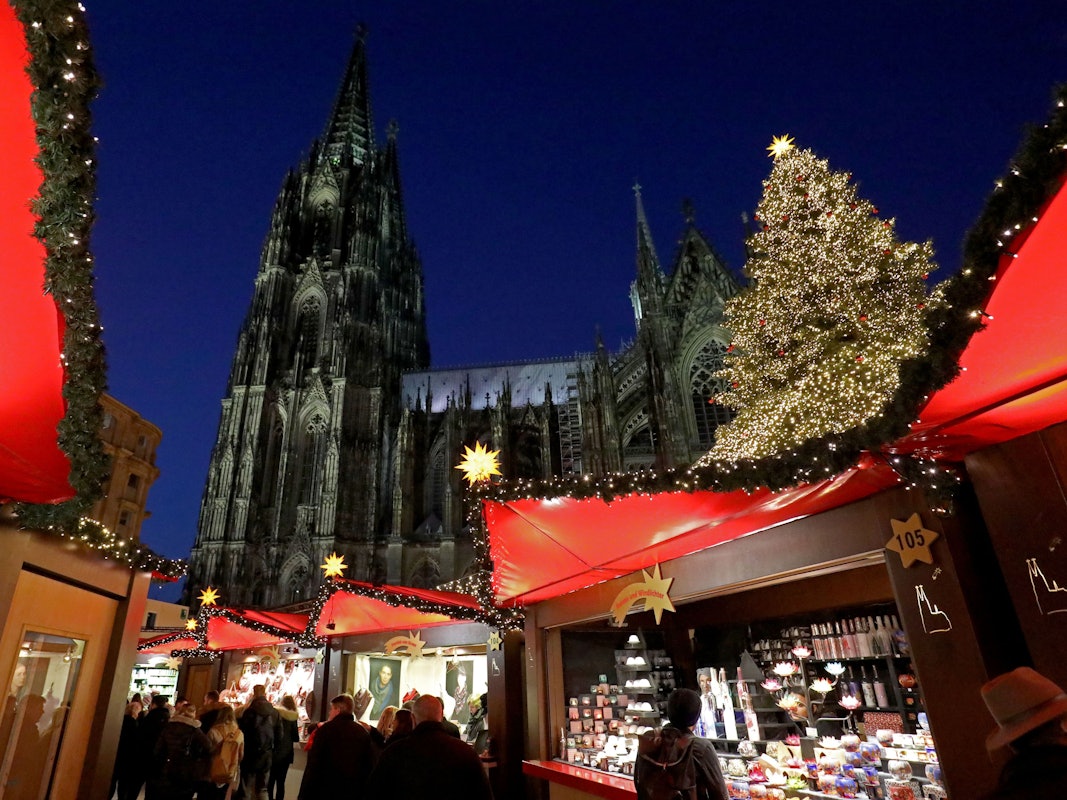 Besucher gehen über den Weihnachtsmarkt vor dem Kölner Dom.