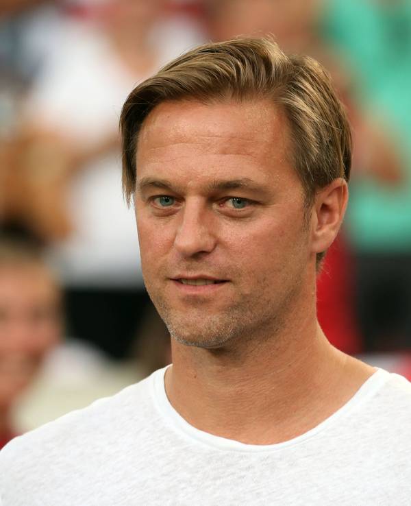 Timo Hildebrand steht vor einem Spiel des VfB Stuttgart in Zivil auf dem Rasen.