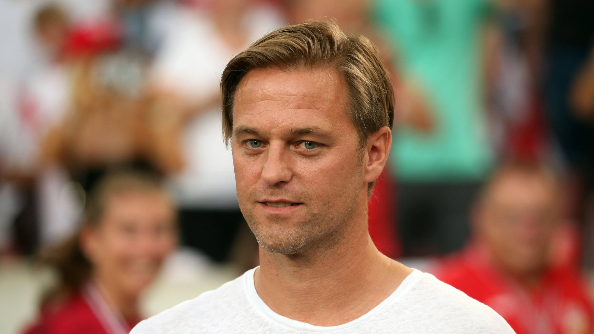 Timo Hildebrand steht vor einem Spiel des VfB Stuttgart in Zivil auf dem Rasen.