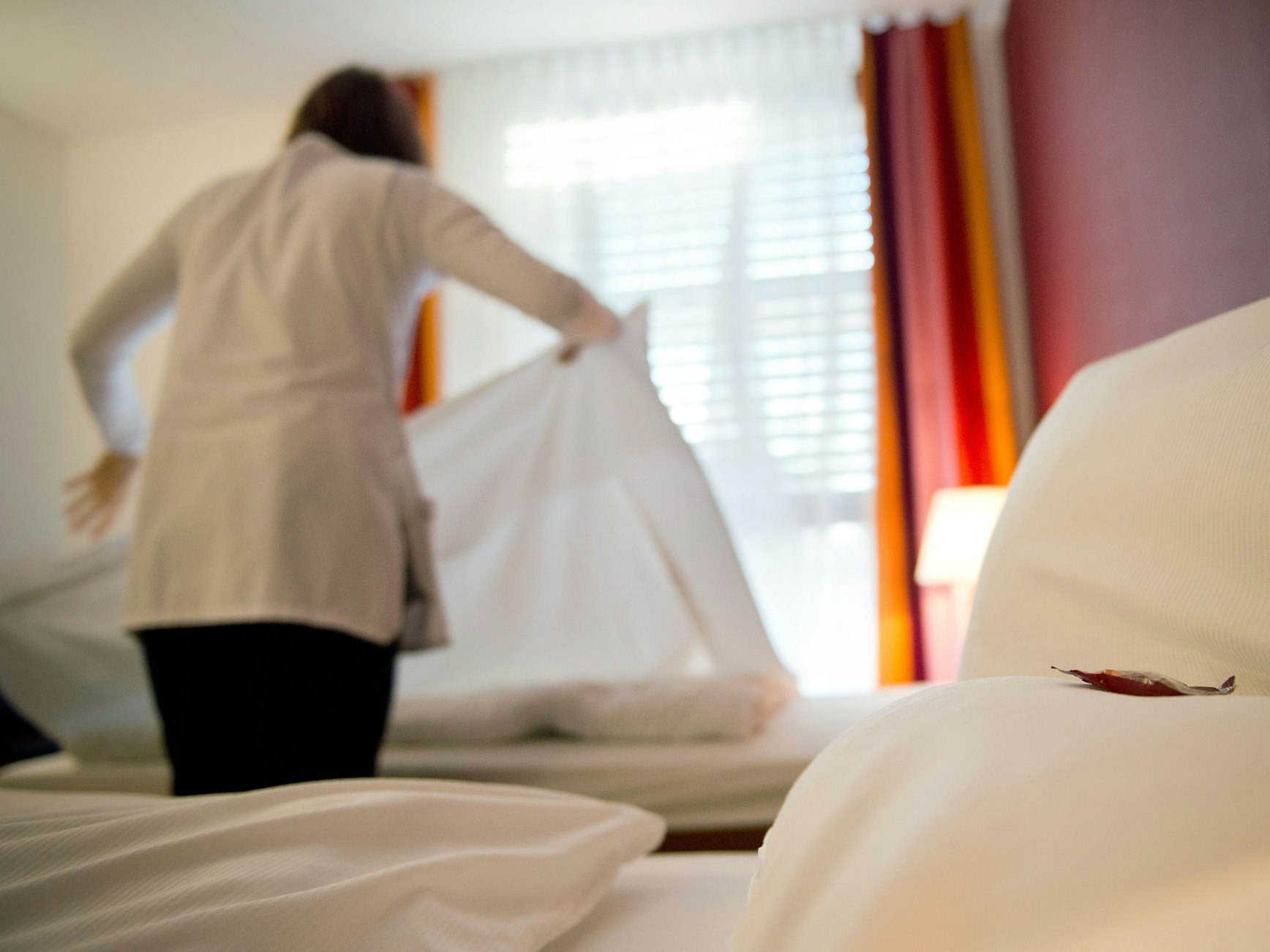 Eine Hotelangestellte macht die Betten in einem Zimmer.