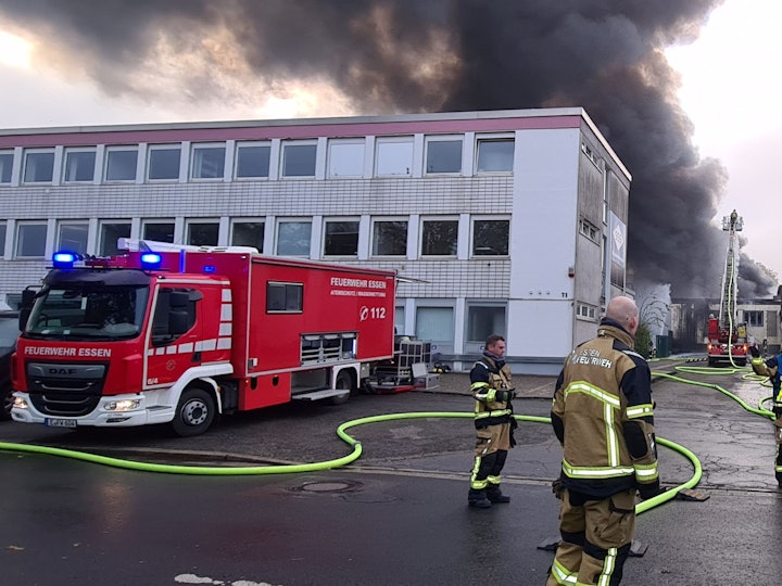 Feuerwehrleute löschen den Brand in der Lagerhalle einer Textildruckfirma.