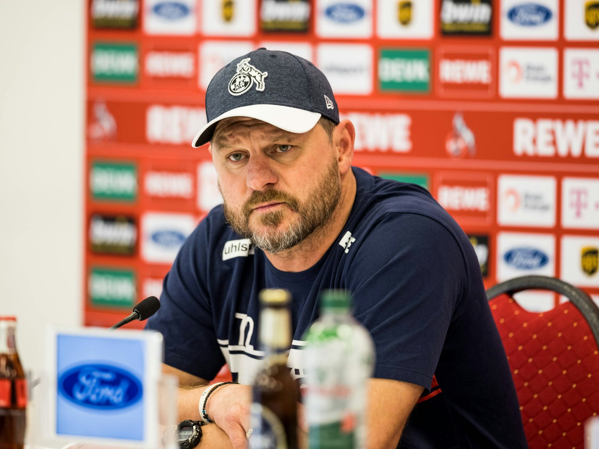 Steffen Baumgart mit skeptischem Blick bei der Pressekonferenz des 1. FC Köln vorm Spiel gegen Bayer Leverkusen.