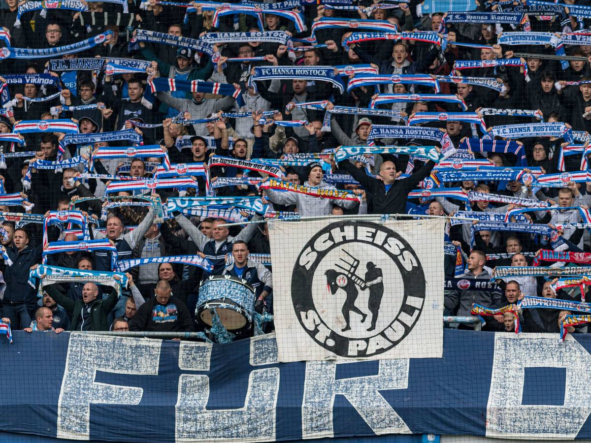 Fans von Hansa Rostock halten ein Banner gegen den FC St. Pauli hoch.